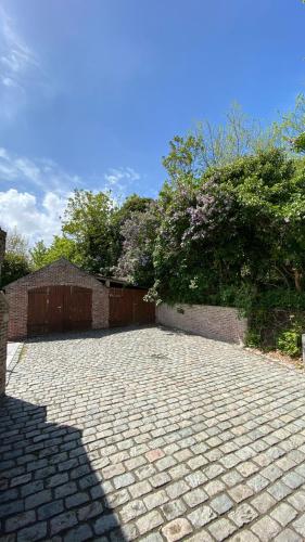 a brick driveway with a fence and flowers on it at Tidal Nest - North Sea Stays in Wenduine