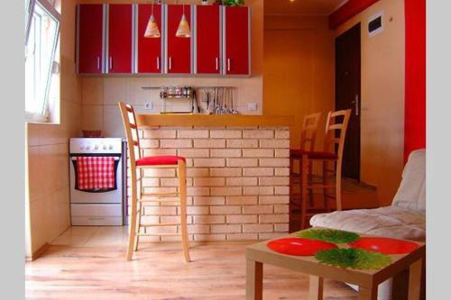 a kitchen with red cabinets and a table and chairs at Apartman Budva Ivana in Budva