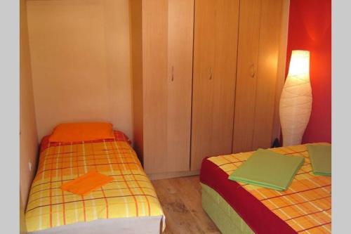 two beds in a small room with a lamp at Apartman Budva Ivana in Budva