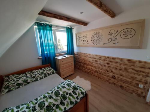 a bedroom with a bed and a window with blue curtains at Domek u Andrzeja 2 in Ciche
