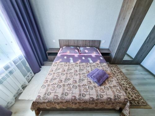 Un dormitorio con una cama con sábanas y almohadas púrpuras. en Элитные апартаменты в Центре, en Semey