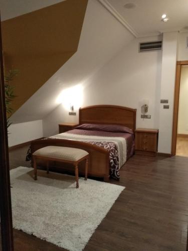 a bedroom with a bed and a bench in a room at Hotel Rural Finca Aldeola in Malpica