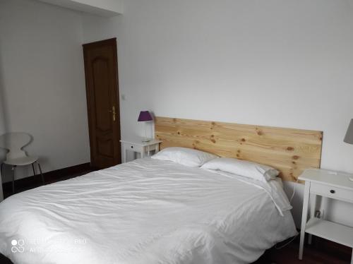 カサラレイナにあるCasa del Abuelo - San Lorenzoの白いベッド1台(木製ヘッドボード付)が備わるベッドルーム1室が備わります。
