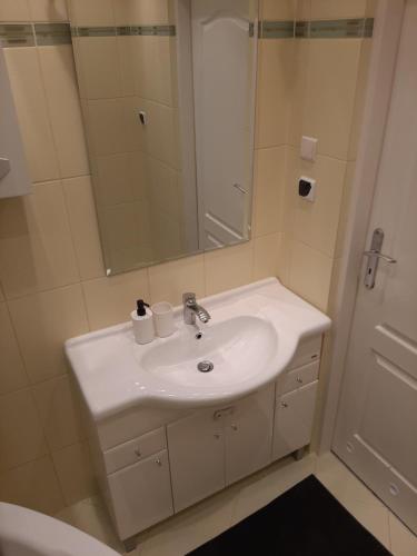 La salle de bains est pourvue d'un lavabo blanc et d'un miroir. dans l'établissement Apartament Bella, à Bolesławiec