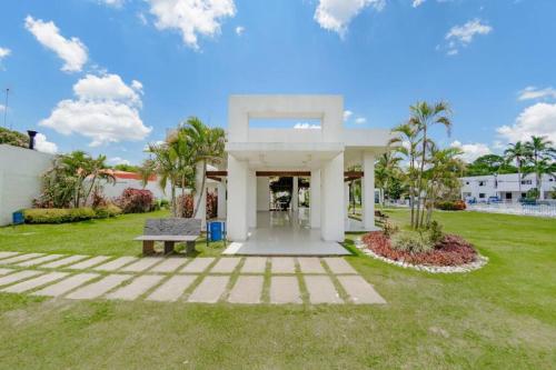 una casa blanca con un banco en un patio en Departamento Planta Baja con parqueo en Condominio en Santa Cruz de la Sierra