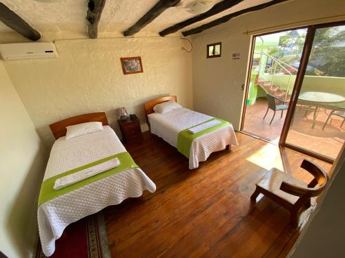 a room with two beds and a balcony with a table at Hostal Casa Edén in Puerto Ayora