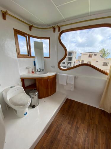 baño con aseo y lavabo y ventana en Hostal Casa Edén, en Puerto Ayora