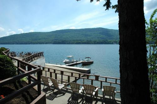 a dock with chairs and a boat in the water at Park Lane Motel in Lake George