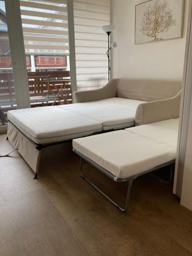 2 camas y un sofá en una habitación con ventana en Kalno namai - apartamentas Juodkrantėje en Juodkrantė