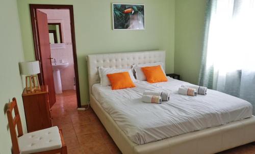 a bedroom with a white bed with orange pillows at Casa Tucano in Aljezur