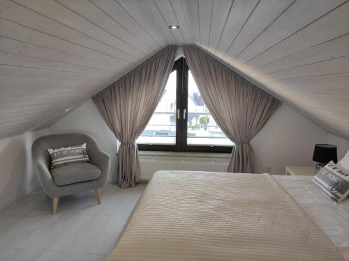 a bedroom with a bed and a chair and a window at Sun&Sea in Jastarnia