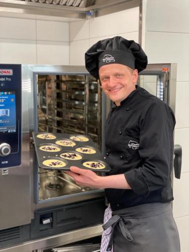 a chef standing in front of an oven with cupcakes at Pfannkuchenhaus Fehmarn in Burg auf Fehmarn