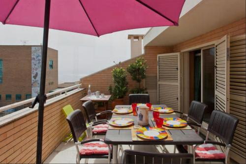 a table and chairs with an umbrella on a balcony at Aguda Beachfront Apartment in Aguda