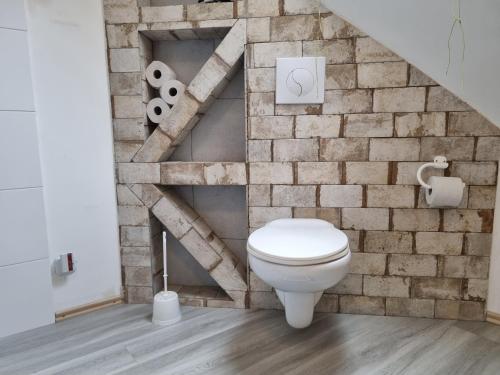 a bathroom with a toilet in front of a brick wall at Ferienwohnung/Monteurwohnung Alte Scheune bei Kassel in Weimar