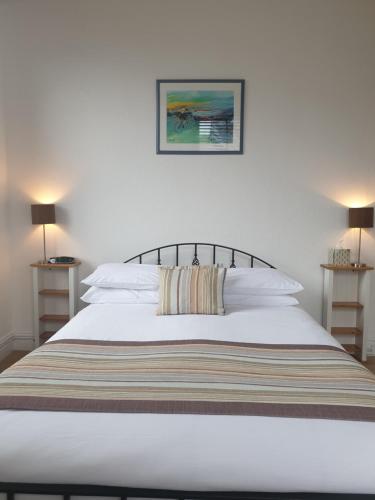 a bedroom with a white bed with a striped blanket at Compston House B & B in Ambleside