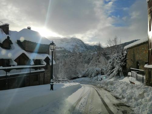 a snow covered street with a street light and a mountain at Los Altos de Escarrilla - tucasaenlospirineos in Escarrilla