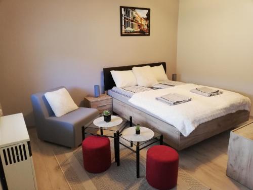 a bedroom with a bed and a chair and tables at D&D Studio Apartment in Subotica