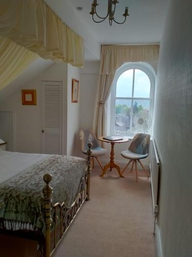a bedroom with a bed and a table and a window at Denehurst Guest House - Adults Only in Windermere