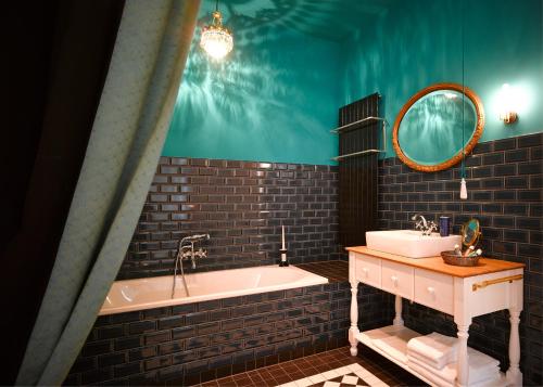 a bathroom with a tub and a sink and a mirror at Gorki Apartments in Berlin