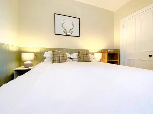 a bedroom with a large white bed with pillows at Cairngorm Guest House in Aviemore