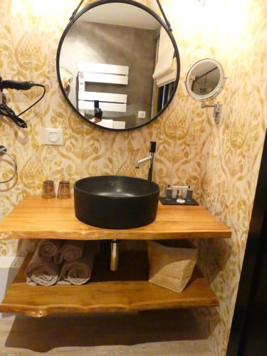 a bathroom with a black sink and a mirror at Le Chapeau Rouge in Lusignan