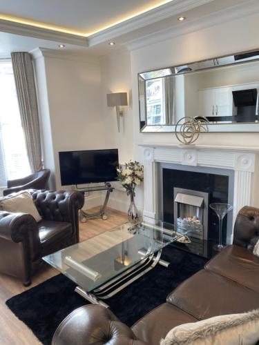 a living room with a fireplace and a glass table at The Maureen Suite in Llandudno