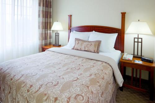 a hotel room with a bed with two lamps and a phone at Staybridge Suites Cranbury - South Brunswick by IHG in Cranbury