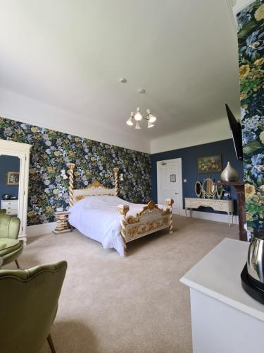a bedroom with a large bed with floral wallpaper at Broom Hall Country Hotel in Saham Toney