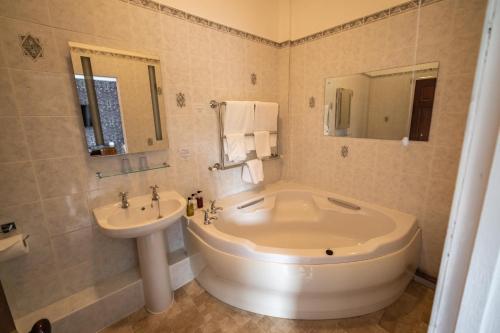 a bathroom with a large tub and a sink at Broom Hall Country Hotel in Saham Toney