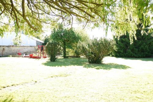 a yard with two trees and a building at Le Chapeau Rouge in Lusignan