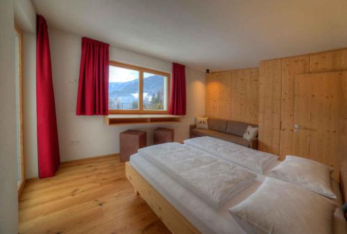um quarto com uma cama grande e uma janela em Hof Unterguggenberg em San Lorenzo di Sebato