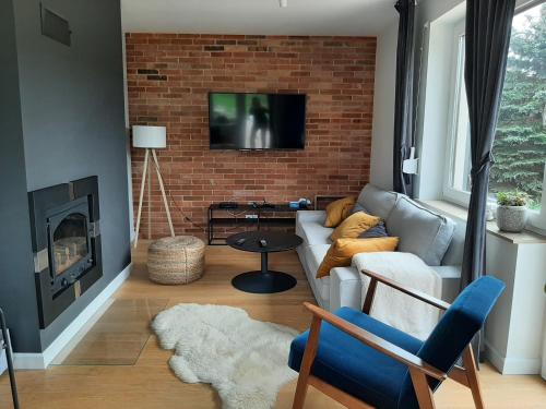 a living room with a couch and a brick wall at VILLA DANUTA- WISELKA, direct at National Park, big garden, 4 bedrooms, private SAUNA in Wisełka
