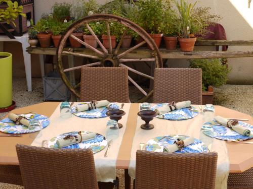 a wooden table with chairs and aokedoked wheel at Le Chapeau Rouge in Lusignan