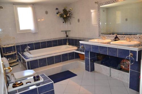 a blue and white bathroom with two sinks and a tub at Maison au Castellet in Le Castellet