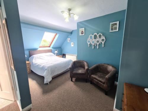 a bedroom with blue walls and a bed and a chair at Broom Hall Country Hotel in Saham Toney