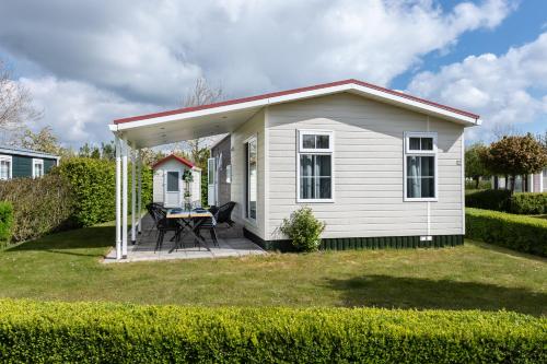 a small white shed with a table in a yard at Luxe 5-persoons chalet op familiecamping in Baarland