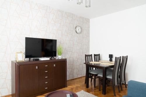uma sala de jantar com uma televisão e uma mesa com cadeiras em Własne M-Studio CENTRUM parter em Konin