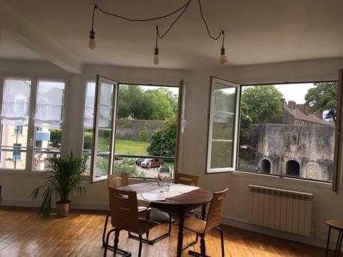 Un comedor con mesa y sillas y ventanas. en DRINOU HOUSE, en Boulogne-sur-Mer