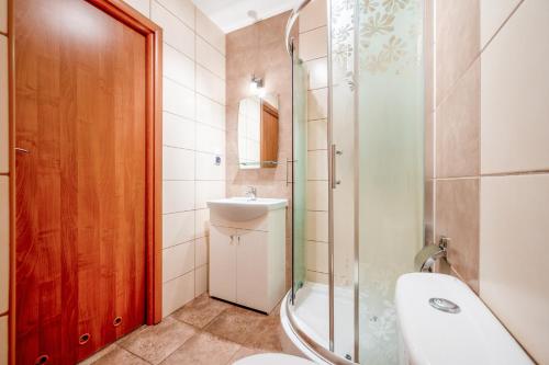 a bathroom with a shower and a sink and a toilet at Apartamenty Plazowa in Darłówko
