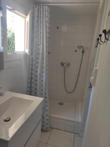 a white bathroom with a shower and a sink at La Glycine Tropézienne in Saint-Tropez