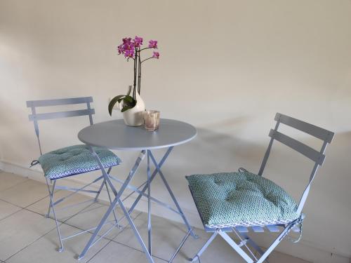 a table with two chairs and a vase with flowers at La Glycine Tropézienne in Saint-Tropez