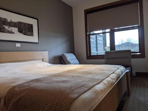 1 dormitorio con cama, ventana y silla en Escapade Bonheur, en Lac-Supérieur
