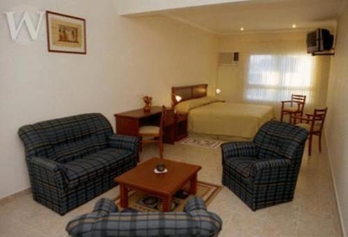 sala de estar con 2 sillas y 1 cama en Wilson Hotel en Salta