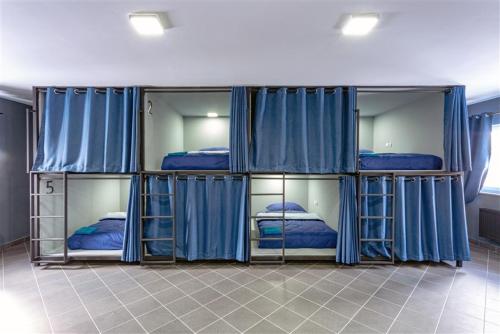 een kamer met 4 stapelbedden en blauwe gordijnen bij Hostel IRON CUBE in Stružná