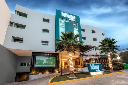 a hotel with palm trees in front of a building at InHouse Culiacán in Culiacán