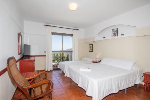 a hotel room with two beds and a balcony at Hotel y Bungalows Balcón de Competa in Cómpeta