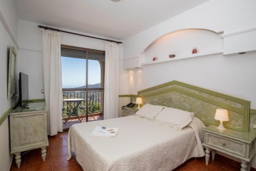 a bedroom with a large bed and a balcony at Hotel y Bungalows Balcón de Competa in Cómpeta