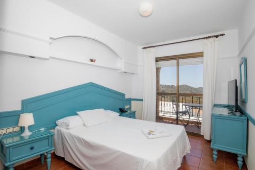a blue and white bedroom with a bed and a window at Hotel y Bungalows Balcón de Competa in Cómpeta