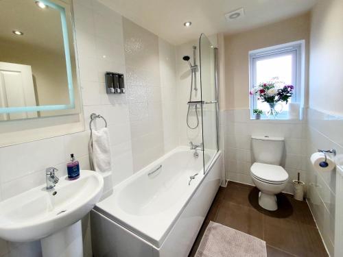 ein Badezimmer mit einer Badewanne, einem Waschbecken und einem WC in der Unterkunft Meadow View, luxury home in heart of England in Shirebrook