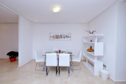 une salle à manger blanche avec une table et des chaises blanches dans l'établissement Privat Apartments Prestigia Hay Riad, à Rabat